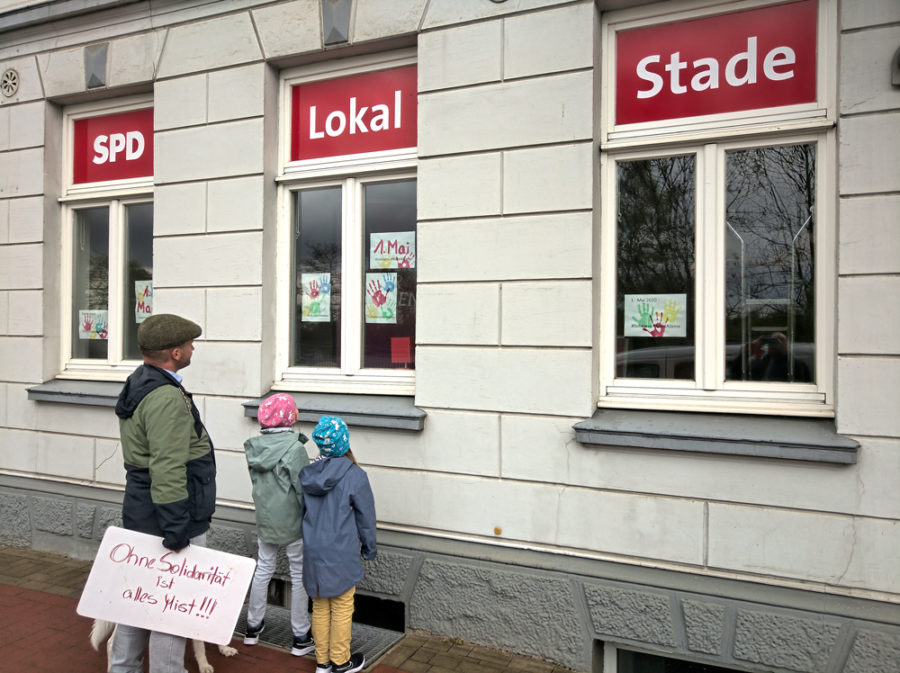 Kai Koeser und weitere Personen schauen sich die Fenster des SPD Lokal Stade zum 1. Mai 2020 an.
