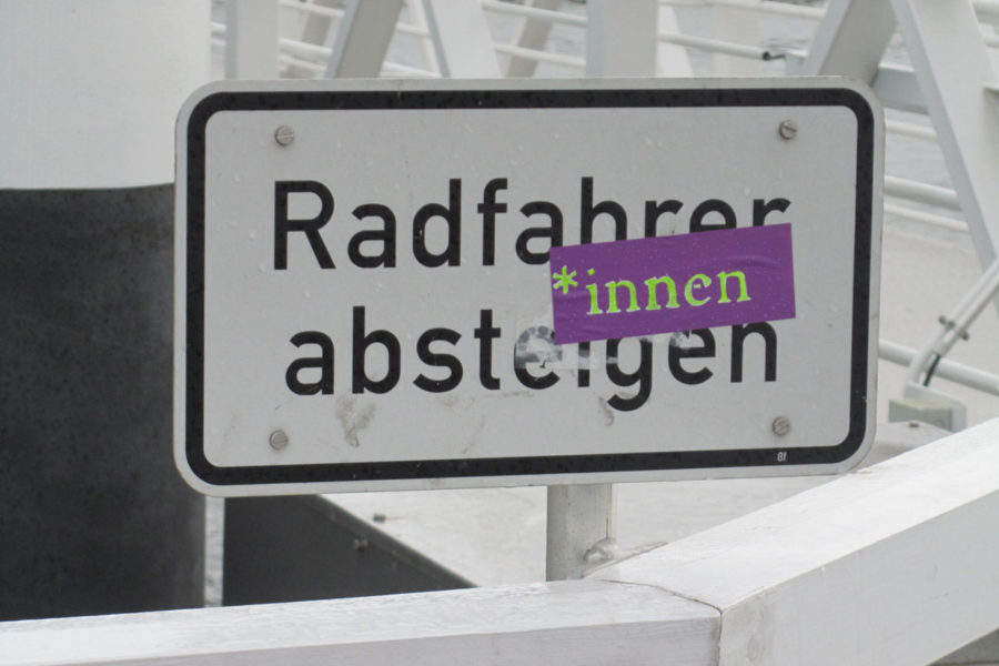 Radfahrer*innen absteigen: Aufkleber an einem Hinweisschild in Kiel (Hörnbrücke)