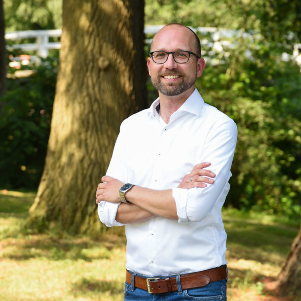 Christian Häckl im Park auf der Museumsinsel in Stade, im Hintergrund eine weiße Brücke über den Burggraben
