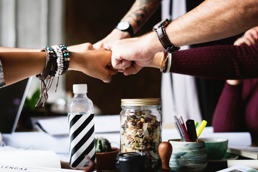 Menschen arbeiten gemeinsam an einem Projekt und machen eine Team-Geste mit der Faust